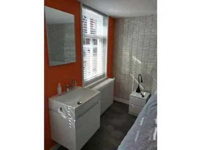 a bathroom with a white sink and a window at Centraal aan Zee in Egmond aan Zee
