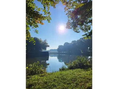 a view of a lake with the sun in the sky at Apartment in Naarden with swimming pool in Naarden