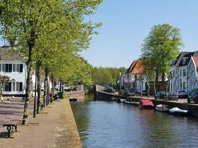 a river in a town with cars parked on the side at Apartment in Naarden with swimming pool in Naarden