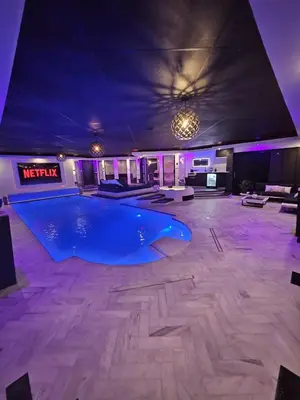 a large swimming pool in a room with purple lighting at Bed & Wellness Malina deluxe in Lelystad