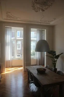 a dining room with a table and chairs and windows at Entire home with direct Vondelpark view in Amsterdam