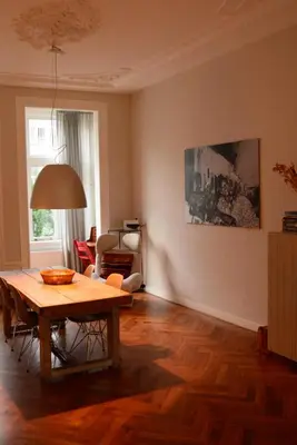 a living room with a wooden table and a living room with a couch at Entire home with direct Vondelpark view in Amsterdam