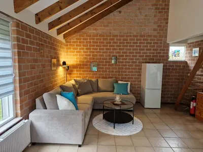 a living room with a couch and a brick wall at Ferienhaus Sunny's Place in Egmond aan den Hoef