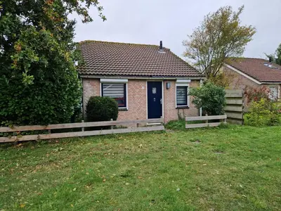 a brick house with a blue door in a yard at Ferienhaus Sunny's Place in Egmond aan den Hoef