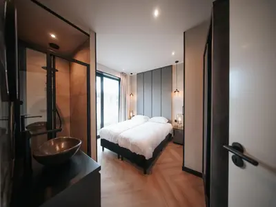 a bedroom with a bed and a bathroom with a sink at Beautiful holiday home in Waarland in Waarland