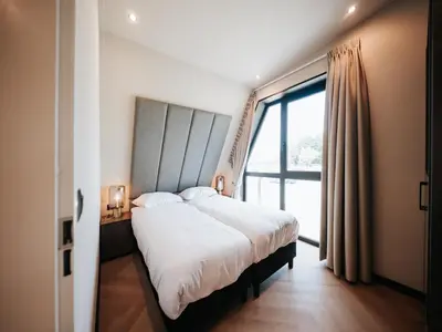 a bedroom with a large bed and a large window at Beautiful holiday home in Waarland in Waarland