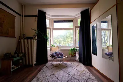a living room with a large window and a chair at Olympic's Little Palace in Amsterdam