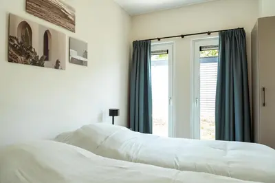 a bedroom with a white bed and a window at Kaag Villas in Warmond