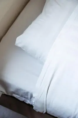 an unmade bed with white sheets and pillows at Kaag Villas in Warmond