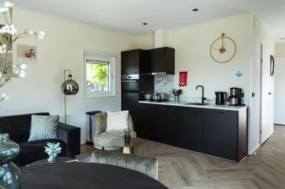 a kitchen with black cabinets and a living room at Kaag Villas in Warmond