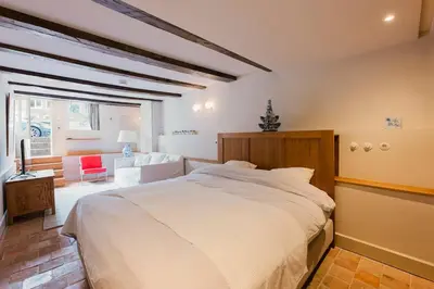 a bedroom with a white bed and a red chair at Charming souterrain studio at Bloemgracht 30 in Amsterdam