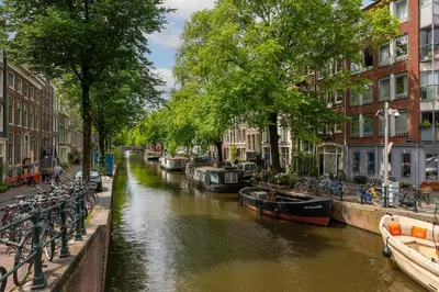 a canal with boats in a city with buildings at Charming souterrain studio at Bloemgracht 30 in Amsterdam