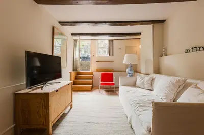 a living room with a white couch and a flat screen tv at Charming souterrain studio at Bloemgracht 30 in Amsterdam