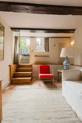 a living room with a red chair and a couch at Charming souterrain studio at Bloemgracht 30 in Amsterdam