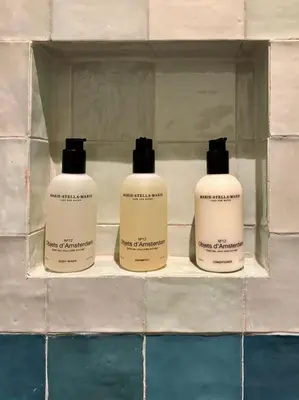three bottles of soap on a shelf in a bathroom at Moyeni in Zandvoort