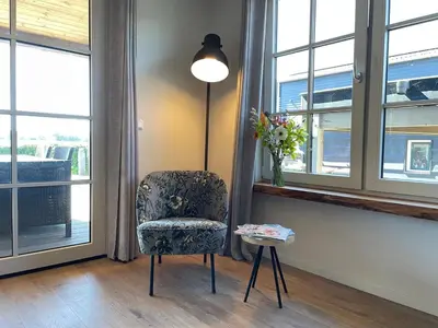 a room with a chair and a table and windows at De Tuinkamer in Egmond aan den Hoef