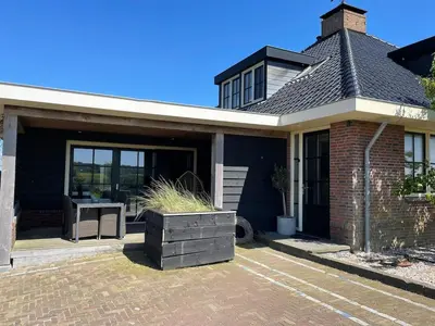 a house with a patio with a table in it at De Tuinkamer in Egmond aan den Hoef