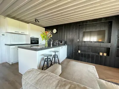 a kitchen with white cabinets and a wooden ceiling at De Tuinkamer in Egmond aan den Hoef
