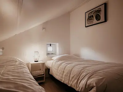 a bedroom with two beds and a mirror on the wall at Apartment Oostergeest 2 by Interhome in Uitgeest