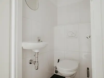 a white bathroom with a toilet and a sink at Apartment Oostergeest 2 by Interhome in Uitgeest
