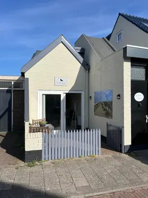 a house with a white fence in front of it at Zeemeeuw aan Zee in Egmond aan Zee