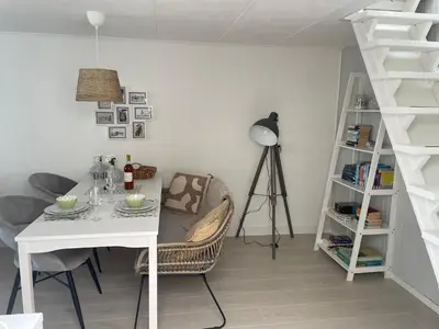 a dining room with a white table and a ladder at Zeemeeuw aan Zee in Egmond aan Zee