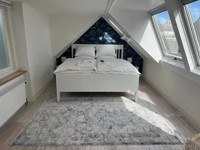 a bedroom with a white bed in a attic at Zeemeeuw aan Zee in Egmond aan Zee
