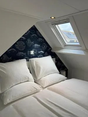a bedroom with two white pillows and a window at Zeemeeuw aan Zee in Egmond aan Zee