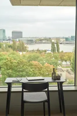 a desk with a chair in front of a window at Wilde Aparthotels Amsterdam Noord in Amsterdam