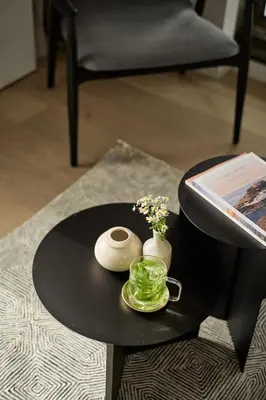 a black table with a vase of flowers on it at Wilde Aparthotels Amsterdam Noord in Amsterdam