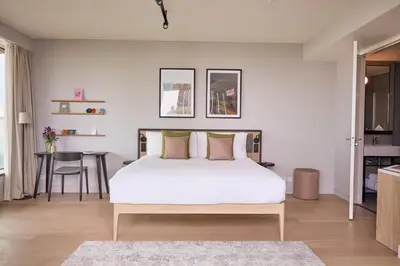 a bedroom with a white bed and a table at Wilde Aparthotels Amsterdam Noord in Amsterdam