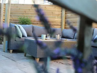 a couch on a patio with two cups on a table at One-bedroom apartment in Heemskerk