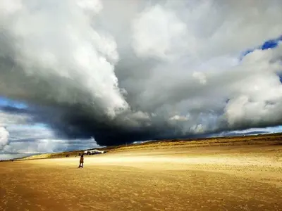 a person standing on a beach under a cloudy sky at One-bedroom apartment in Heemskerk