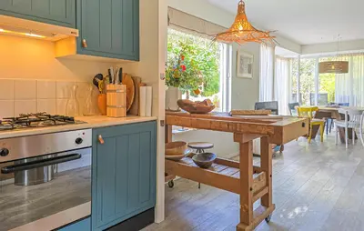 a kitchen with blue cabinets and a table and a dining room at 2 Bedroom Beautiful Home In Noordwijkerhout in Noordwijkerhout