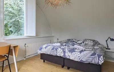 a bedroom with a bed with a blue and white comforter at 2 Bedroom Beautiful Home In Noordwijkerhout in Noordwijkerhout
