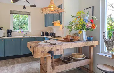 a kitchen with blue cabinets and a wooden island with flowers at 2 Bedroom Beautiful Home In Noordwijkerhout in Noordwijkerhout
