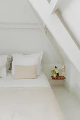a white bed with white pillows in a white room at Sea and the City in Overveen