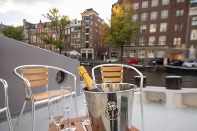 a bucket with a bottle of wine and glasses on a balcony at Canal Suite on Houseboat in Amsterdam