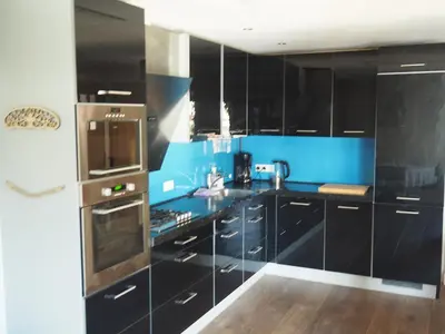 a kitchen with black cabinets and a blue wall at The perfect spot in Akersloot