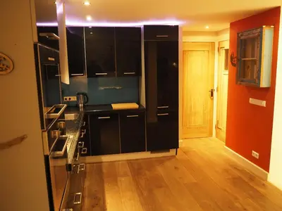 a kitchen with black cabinets and a wooden floor at The perfect spot in Akersloot