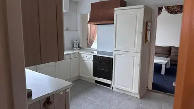a kitchen with white cabinets and a black stove at Zaanvilla in Wormerveer