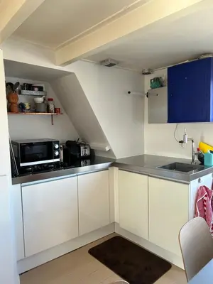 a small kitchen with white cabinets and a microwave at Top floor apartment at Westerpark and Jordaan in Amsterdam