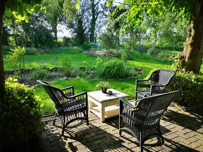 a patio with three chairs and a table in a yard at South African lodge in Westbeemster