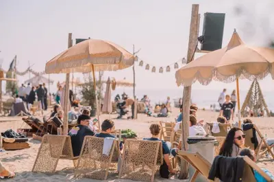 a group of people sitting on a beach with umbrellas at Little Magic Zandvoort in Zandvoort