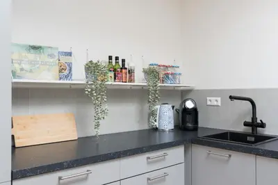 a kitchen with white cabinets and a black counter top at Pakhuis Achter - Rustig gelegen vlakbij Amsterdam & Zaanse Schans in Wormerveer