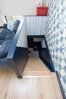 a living room with a couch under a staircase at Pakhuis Achter - Rustig gelegen vlakbij Amsterdam & Zaanse Schans in Wormerveer