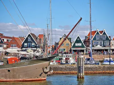 a boat is docked in a harbor with houses at Pakhuis Achter - Rustig gelegen vlakbij Amsterdam & Zaanse Schans in Wormerveer