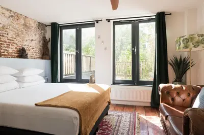 a bedroom with a bed and a couch and windows at Herenstraat Residence in Amsterdam