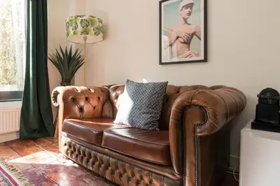 a brown leather couch sitting in a living room at Herenstraat Residence in Amsterdam