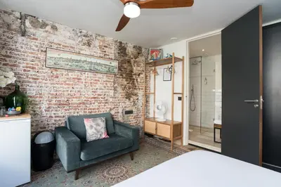 a bedroom with a chair and a brick wall at Herenstraat Residence in Amsterdam